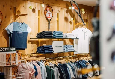 A modern clothing store with wooden shelves and well-organized accessories. A mannequin in sporty clothing stands in the middle of the room.