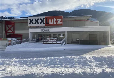 Ein Möbelhaus mit dem Namen "XXX Lutz" im Winter. Der Eingangsbereich ist mit Schnee bedeckt und die Umgebung sieht winterlich aus.