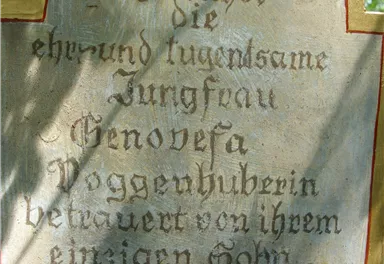 A sign with the inscription about the venerable virgin Genevieve, which is placed in a garden. It is part of a historical site near Kitzbühel.