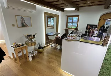 A modern reception area with a wooden ceiling and warm lighting. On the right is a counter with drinks and on the left are seating options.