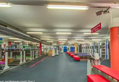 A modern gym with various training equipment and an open space. Benches and machines are neatly arranged, ready for the workout.