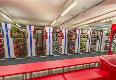 A sales area with shelves displaying various products. In the center, there are red seating furniture for customers.