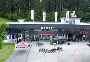 A store for sports equipment with bicycle rental and ski gear. Outside, there are several bicycles and tents.