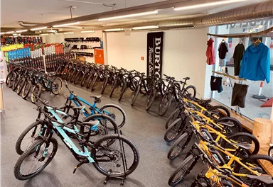 A bicycle shop with many bikes in different colors. The bikes are neatly arranged in rows and are ready for sale.