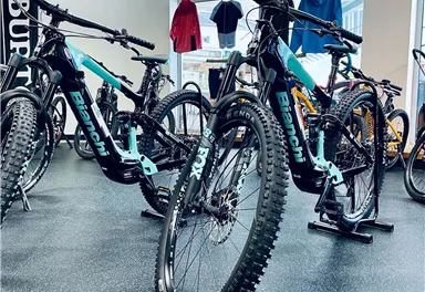 A bike shop with several mountain bikes of the brand Bianchi. The bicycles have striking colors and are displayed on a black floor.