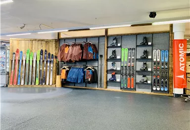 A ski rental with a selection of skis, snowboards, and clothing. The walls are well organized with sports equipment.