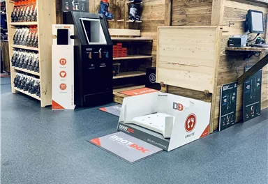 A modern ski rental with wooden shelves and ski equipment. In the foreground is a shoe scanner for customers.