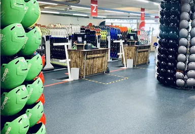 A store with many sports helmets in various colors. In the background, sales stands and equipment are visible.