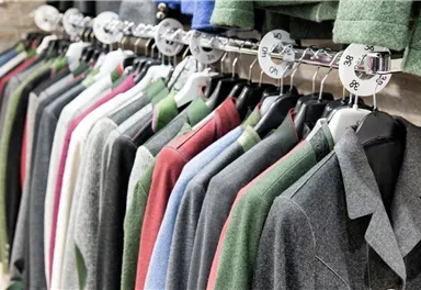 Eine Auswahl an Jacken in verschiedenen Farben hängt ordentlich an einer Kleiderstange. Die Jacken sind aus ähnlichem Stoff und zeigen eine stilvolle Präsentation.