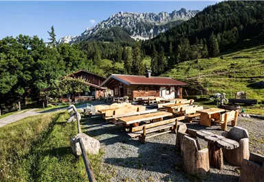 A cozy mountain hut in a mountainous landscape. Wooden tables and benches invite you to linger.