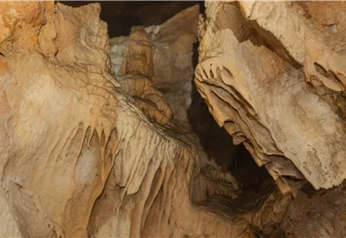 An impressive cave landscape with fascinating stalactites and stalagmites. The rocks display interesting formations and textures.