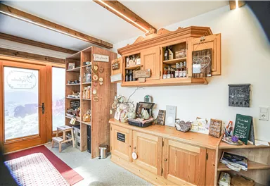 A cozy room with wooden shelves and a workbench. Various decorations hang on the walls, and there is a large window view.