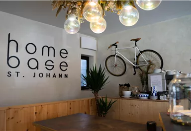 A stylish interior with a wooden counter and modern decorative elements. A bicycle hangs on the wall, and the lighting consists of decorative light bulbs.
