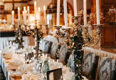 An elegantly decorated table with candle holders and floral arrangements. The table decoration is festive and stylish.