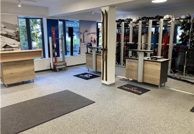 A modern sports store with ski equipment and accessories. The decor is bright and inviting, with space for consultation and sales.