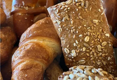 A selection of freshly baked bread and rolls. The image shows different types of bread with toasted sesame and seeds.