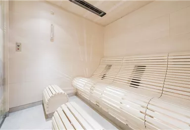 A modern steam bath with bright, wood-colored benches. The walls are designed in a clear and minimalist style.
