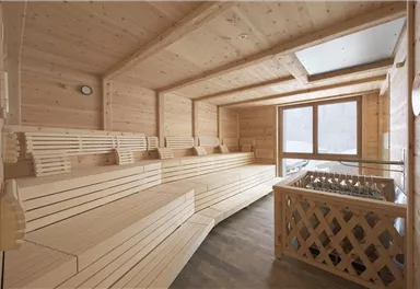 A bright sauna with wooden paneling and comfortable benches. Large windows provide a beautiful view of nature.