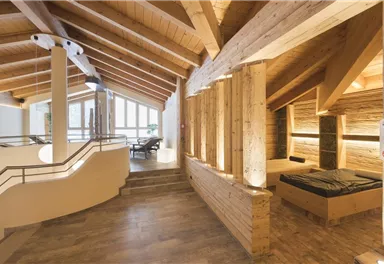 A modern interior with wooden paneling and an open space concept. The room is bright and inviting, with large windows and a cozy seating area.