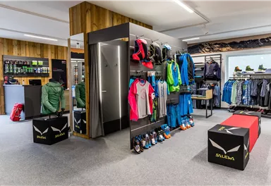 A modern sporting goods store with various outdoor clothing and shoes.  
Wooden walls and a clear, bright space create an inviting atmosphere.