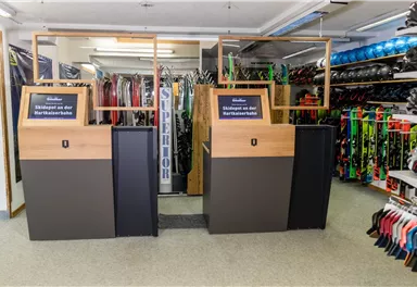 A ski rental with modern dispensing stations. In the background, various skis and equipment are visible.