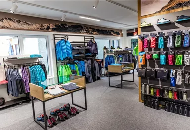 A sporting goods specialty store with a variety of clothing items in different colors. Accessories and equipment for outdoor activities are also displayed on the walls.