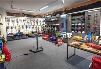 A sports store with a selection of tennis rackets, balls, and sports bags. The shelves are colorful and well-organized.