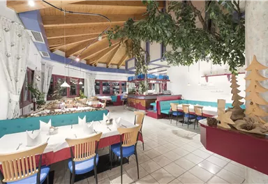 A cozy restaurant with a wooden ceiling and colorful seating. The tables are elegantly set and offer space for many guests.