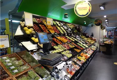 A colorful fruit and vegetable display in a supermarket. Fresh, seasonal products are neatly arranged.