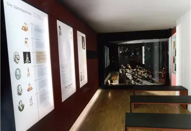 Ein modernes Museum mit Wandtafeln und ausgestellten Objekten. Der Raum ist hell und einladend.