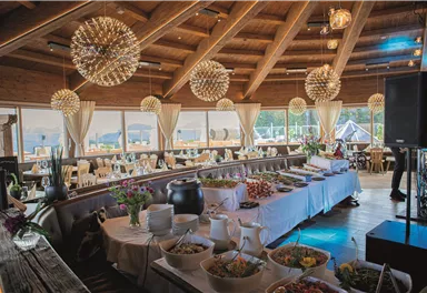 An elegant restaurant with a wooden ceiling and tasteful lighting. Plates with various dishes are ready for the guests.