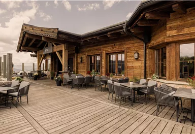 A rustic wooden restaurant with a large terrace. Tables and chairs are ready to welcome guests.