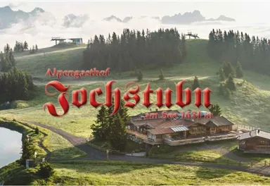 A picturesque mountain landscape with a traditional inn. Surrounded by green meadows and forests, the place offers a tranquil atmosphere.