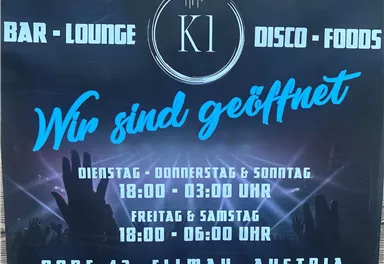 Ein Plakat für eine Bar mit Lounge und Disco. Es steht „Wir sind geöffnet“ und die Öffnungszeiten für Dienstag bis Sonntag sind angegeben.