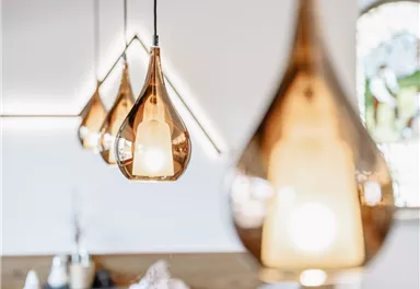 Ein modernes Restaurant mit stilvollen hängenden Lampen. Die Einrichtung ist hell und einladend, mit Holz- und weißen Akzenten.