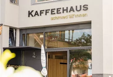 A modern coffee house named "Kaffeehaus" is visible. Guests are sitting outside while the sun is shining.