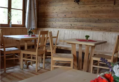 Eine gemütliche Holzhütte mit rustikalen Möbeln und warmem Licht. Der Raum ist einfach gestaltet und eignet sich perfekt für gesellige Zusammenkünfte.