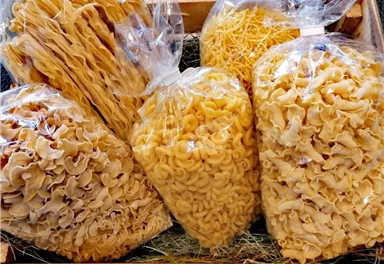 A selection of various pasta in transparent bags. The pasta is presented in different shapes and sizes.