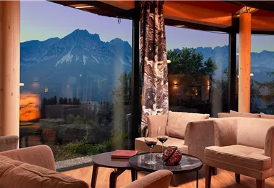 A cozy lounge with a view of majestic mountains in the background.  
Large windows let in plenty of light and create a relaxing atmosphere.