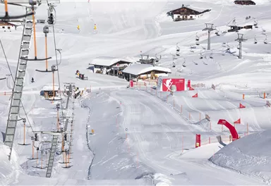 Eine schneebedeckte Landschaft mit Skiliften und einem gemütlichen Skihäuschen. Die Pisten sind gut präpariert und laden zum Skifahren ein.