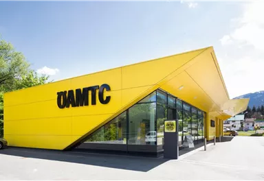 Ein modernes gelbes Gebäude mit großen Fenstern und dem Schriftzug "ÖAMTC". Die Architektur ist auffällig und zeitgemäß.