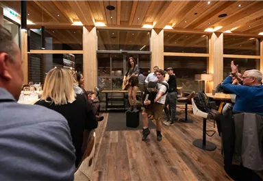 A vibrant atmosphere in a restaurant where a musician performs. Guests are clapping and enjoying the performance.