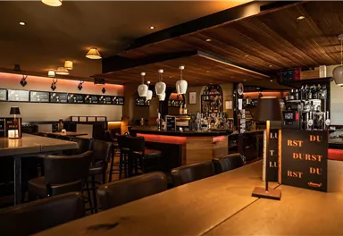 Eine gemütliche Bar mit Holzinterieur und dimmbarer Beleuchtung. Der Thekenbereich ist gut bestückt und einladend.