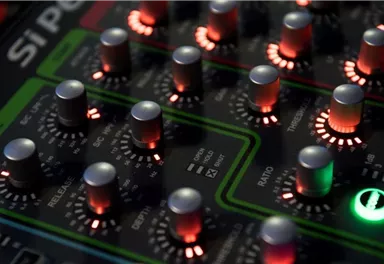 A mixer with luminous sliders and knobs. The green and red lights give the scene a modern look.