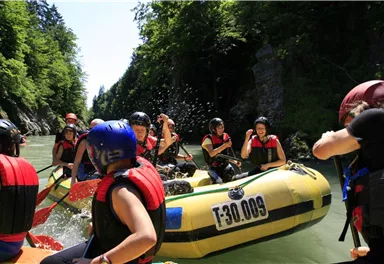 A group of people rafting on a river. The participants are wearing helmets and life jackets and enjoying the thrilling activity in nature.