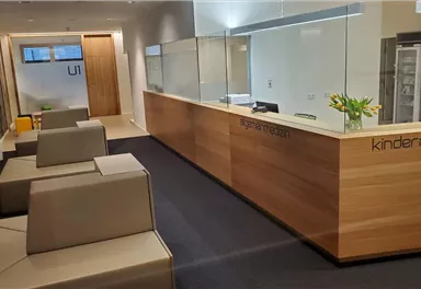 A modern reception area with a reception desk and simple seating furniture. The walls are light, and there are fresh flowers on the desk.