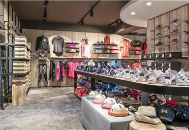 Ein moderner Sportladen mit einer vielfältigen Auswahl an Kleidung und Schuhen. Die Regale sind ordentlich angeordnet und bieten eine einladende Atmosphäre.