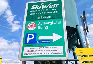 The image shows a sign for the SkiWelt with information about the mountain lifts in Ellmau-Going. It points to the Astbergbahn in Going and includes parking information.