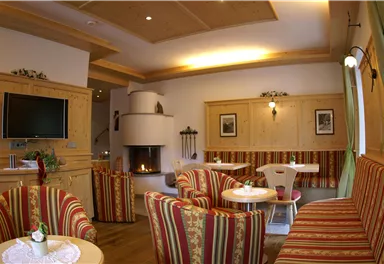 A cozy room with striped sofas and a fireplace. The walls are light and there is a television.