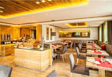 Ein modernes Restaurant mit Holzverkleidung und eleganten Tischen. Die Atmosphäre ist gemütlich, ideal für ein entspanntes Essen.